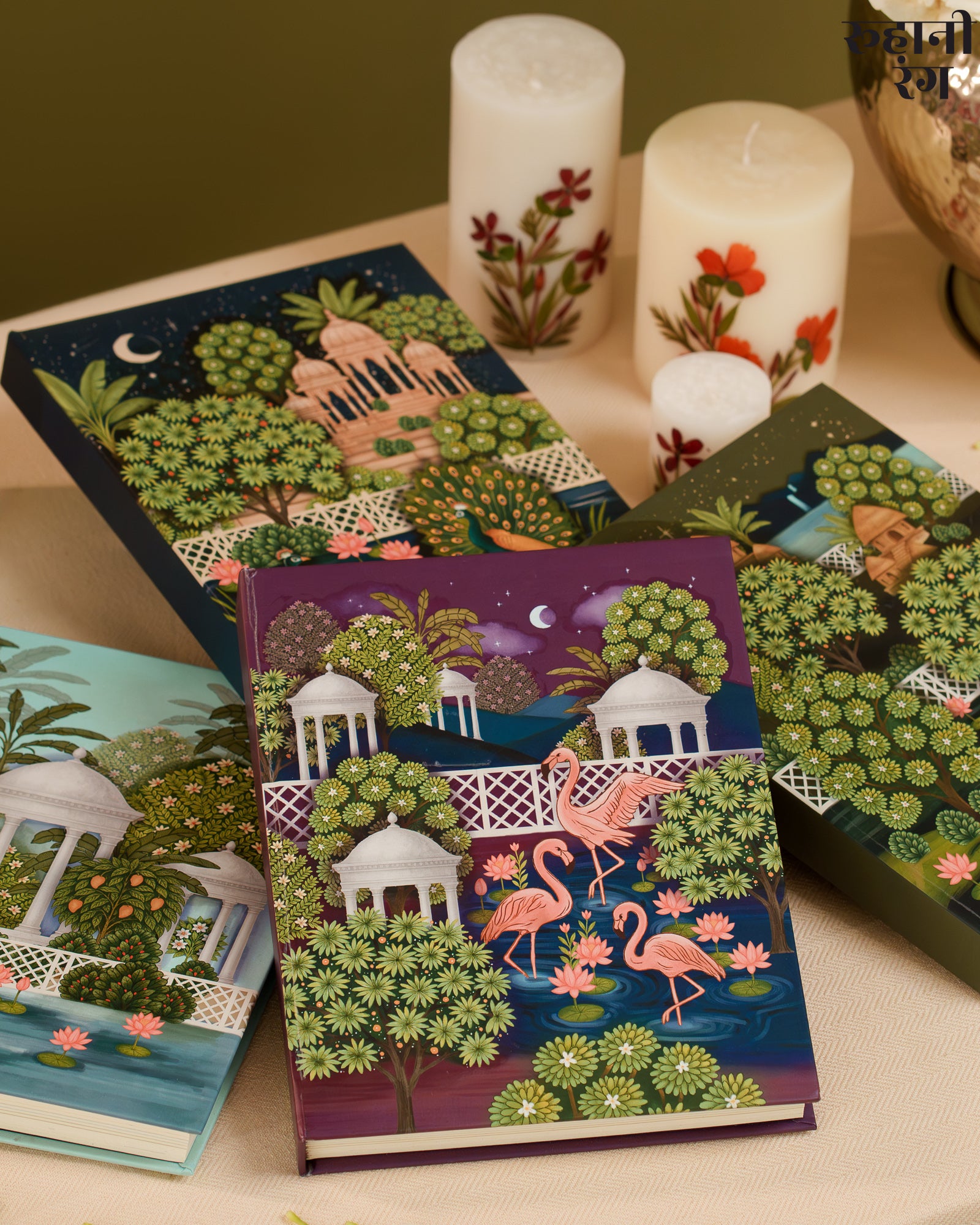 Decorative notebooks and planners 2026 with artistic designs on a table with candles.