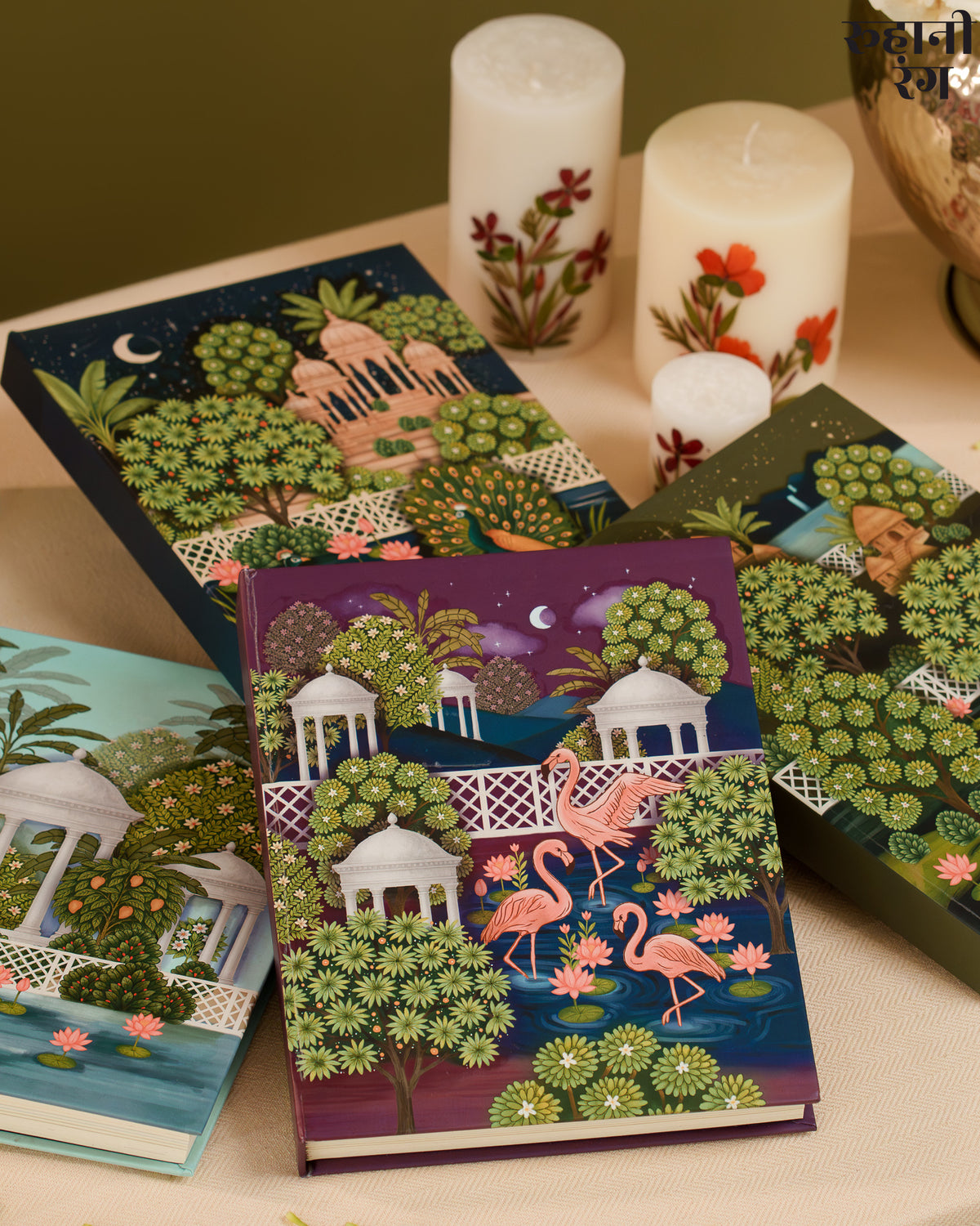 Decorative notebooks and planners 2026 with artistic designs on a table with candles.
