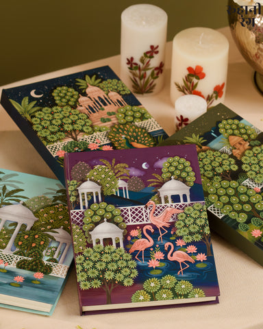 Decorative notebooks and planners 2026 with artistic designs on a table with candles.
