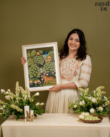 Woman holding a framed artwork with a green background, surrounded by flowers and decor.