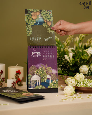Hand holding a decorative calendar with floral design on a table with flowers and candles.