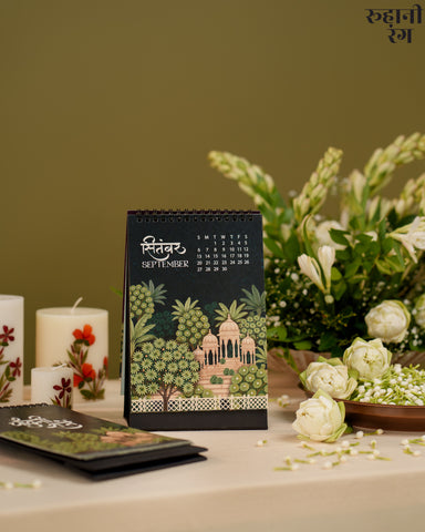 Black calendar with decorative design on a table with flowers and candles