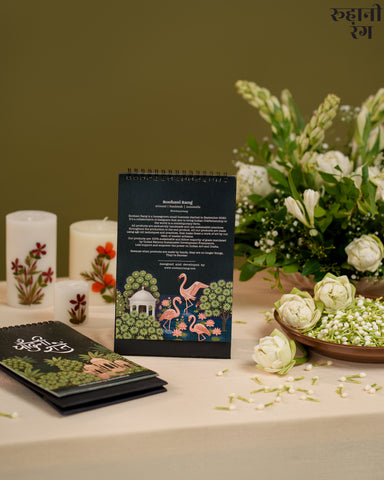 Decorative calendar with floral and flamingo design on a table with candles and flowers.