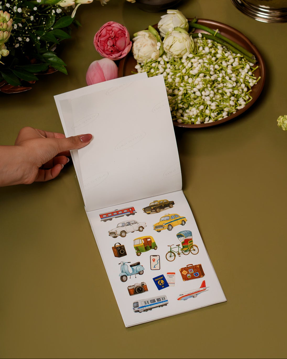 Floral arrangements on a table with a hand holding a card with stickers.